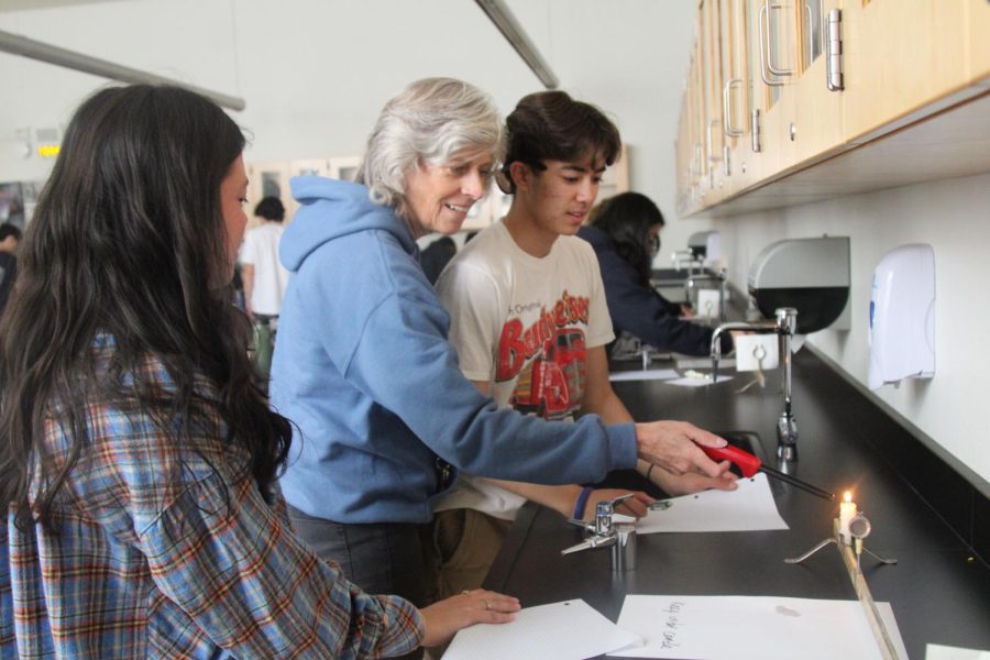 Stahl helps seniors Aily Bencik and Austin Massey light a candle for a physiology lab.