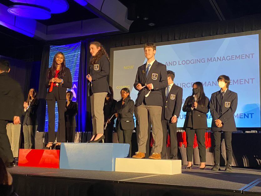 Zach Lachs stands on the podium after receiving his medal at DECA Nationals in Orlando, FL.