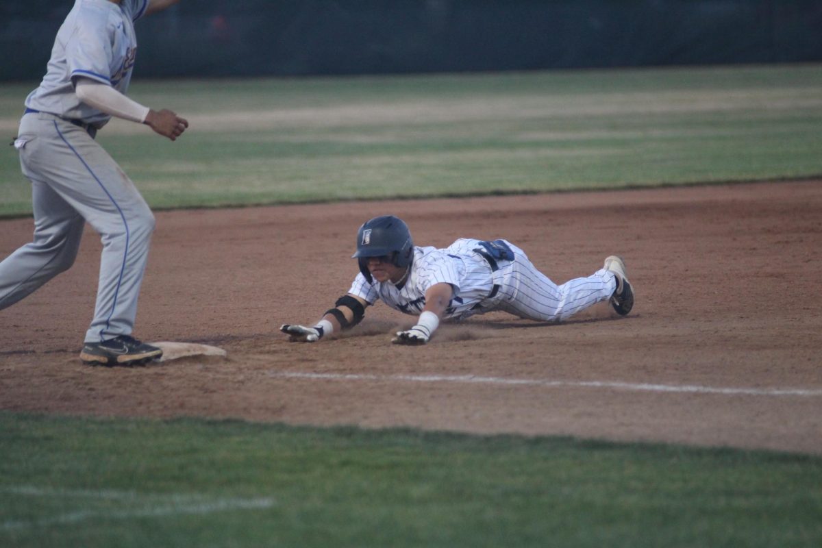 Sophomore Evan Furuichi slides into 3rd base after hitting a triple in the 3rd inning.